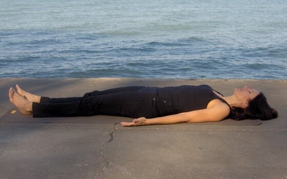 Mulher deitada no chão diante do mar