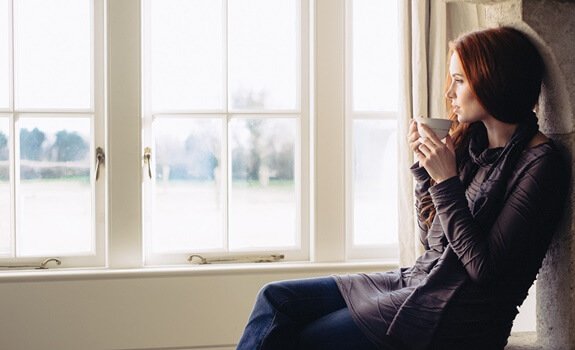 Mulher tomando chá e olhando pela janela