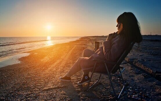 Mulher observando pôr do sol na praia