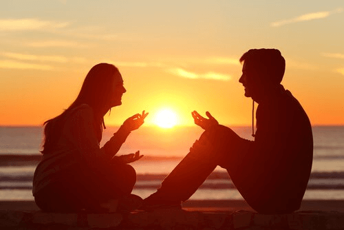 Casal conversando diante do pôr do sol