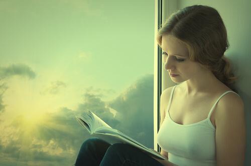 Mulher lendo livro na janela