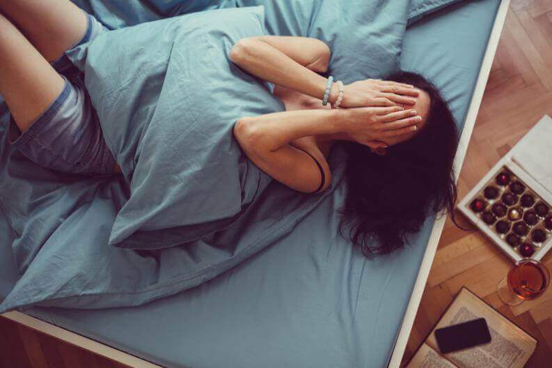 Mulher com insônia rolando na cama