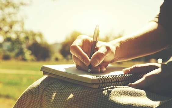 Pessoa escrevendo em caderno