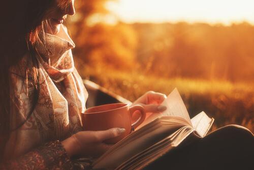 Mulher lendo livro com xícara de café