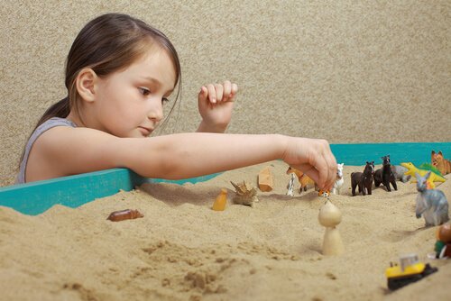 Menina brincando com brinquedos na areia