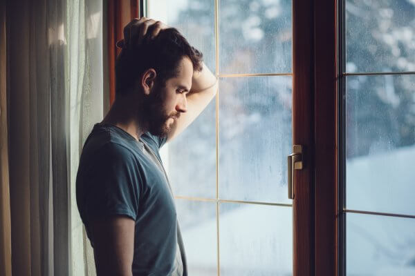 Homem chateado diante da janela