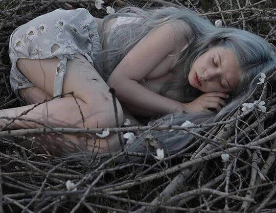 Mulher dormindo em ninho de galhos