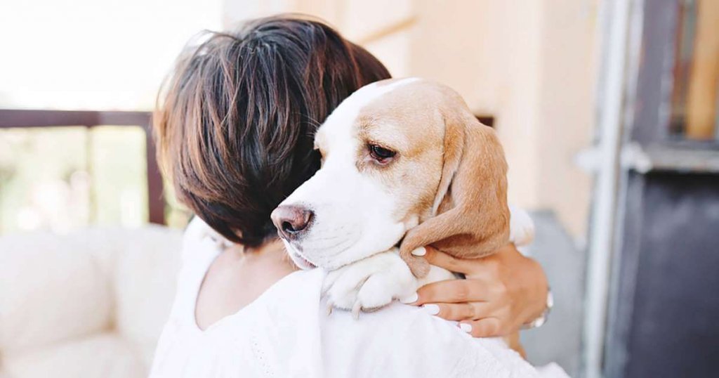 Mulher abraçando seu cachorro