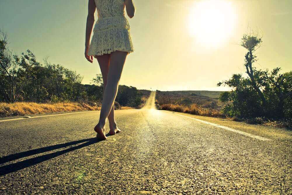 Mulher caminhando sozinha em estrada