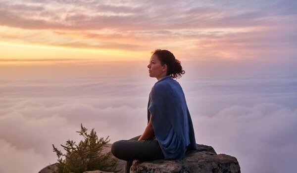Mulher meditando no topo de montanha