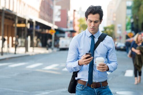 Homem olhando o celular na rua