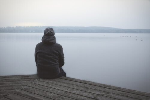 Homem sentado diante de lago