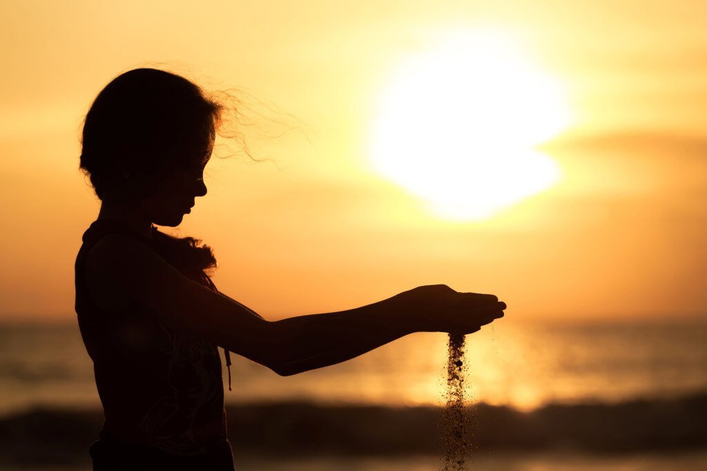Menina mexendo na areia da praia
