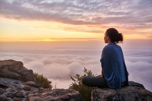 Mulher meditando no topo de montanha
