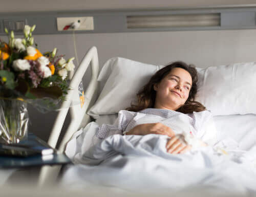 Mulher sorrindo em cama de hospital apesar de doença