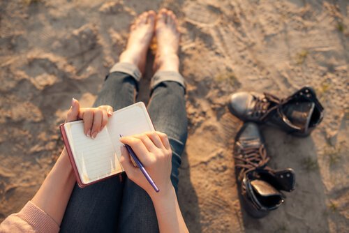 Mulher escrevendo diário na praia