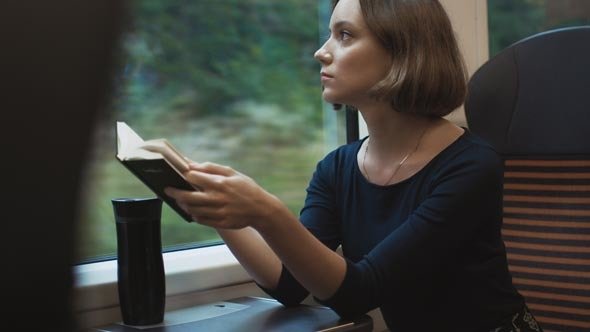 Mulher lendo em trem enquanto viaja