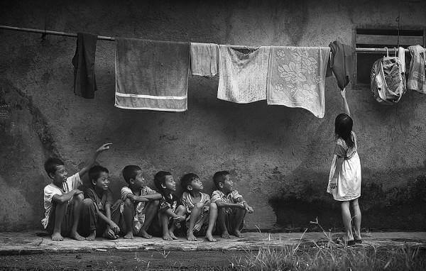 Crianças embaixo de um varal de roupa