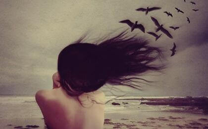 Mulher na praia com vento e pássaros