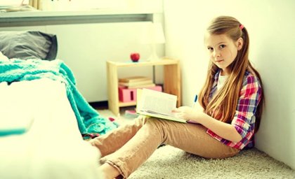 Menina lendo um livro em seu quarto