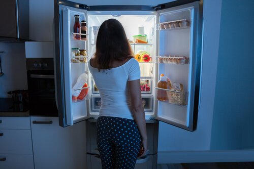 Mulher assaltando a geladeira à noite