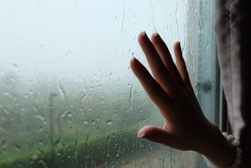 Mão na janela embaçada por chuva