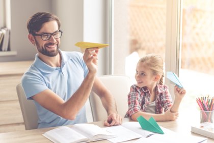 Pai e filha fazendo aviãozinho de papel