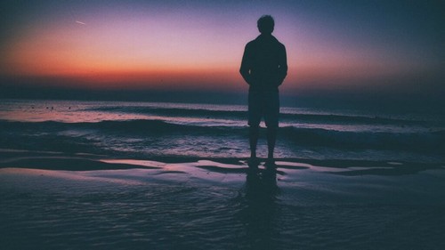 Homem na praia contemplando o horizonte