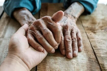 Adulto pegando na mão de um idoso