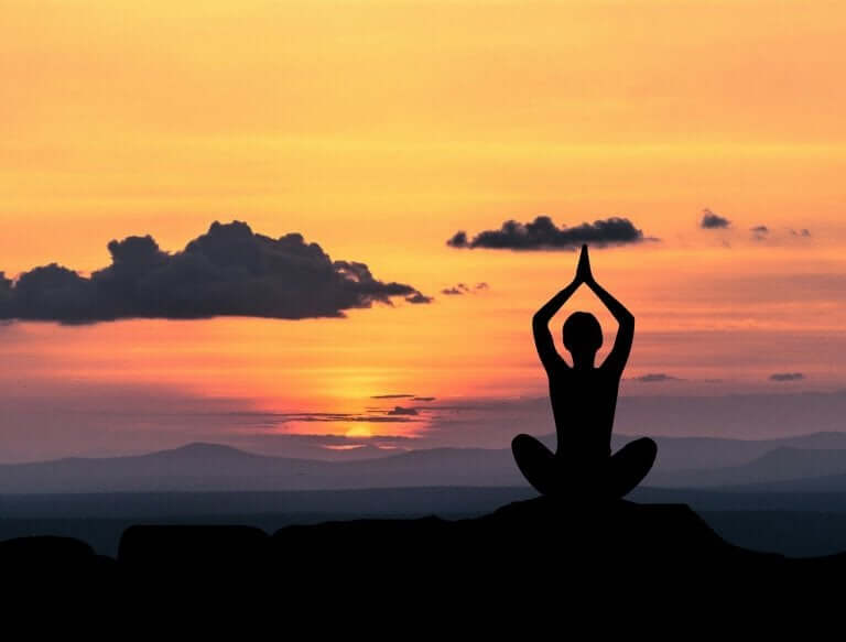 Mulher fazendo ioga no pôr do sol