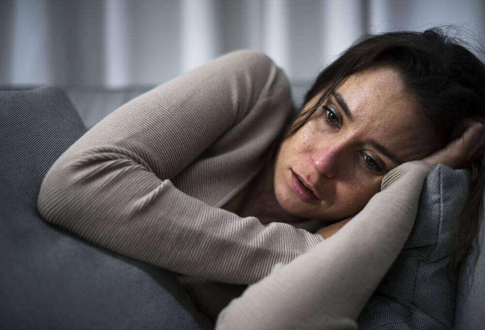 Mulher chorando deitada no sofá