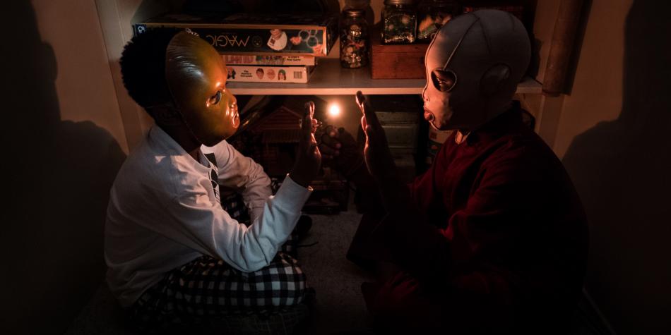 Duas crianças com máscaras no escuro