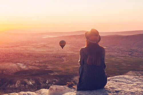 Garota vendo balões em cima de uma montanha