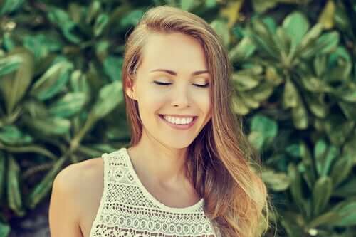 Mulher sorrindo de olhos fechados
