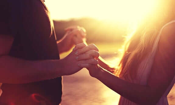 Casal dando as mãos no pôr do sol