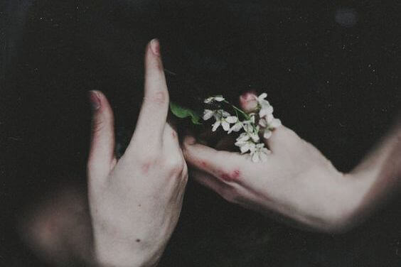Mãos segurando flores brancas