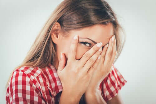 Mulher se escondendo atrás das mãos