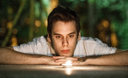 Jovem observando vela acesa