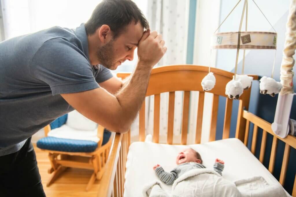 Pai com bebê chorando no berço