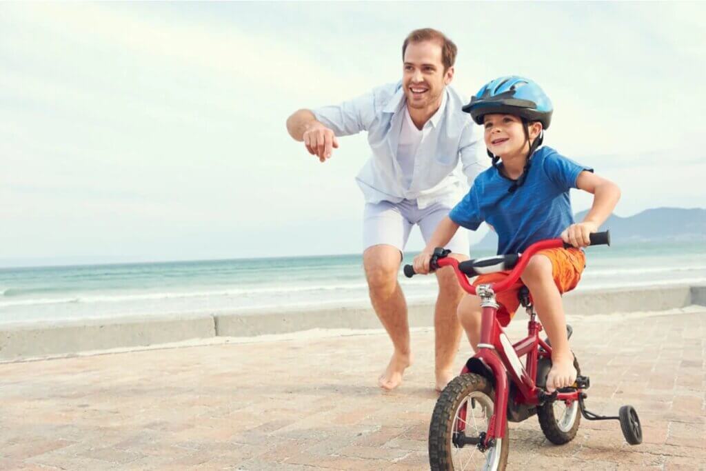 Pai e filho de bicicleta na praia