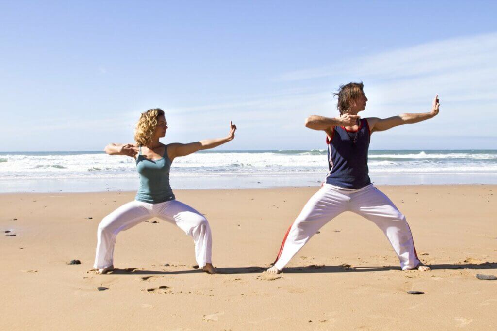 Casal praticando qi gong na praia