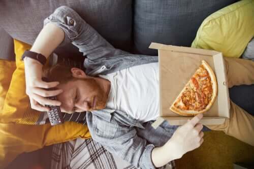 Homem comendo pizza no sofá