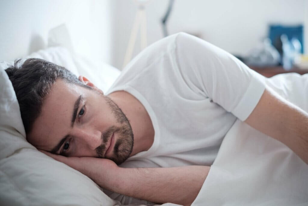 Homem deitado na cama preocupado