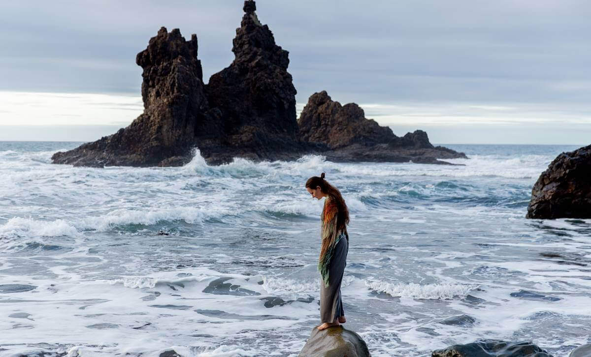 Mulher em pedra na beira do mar