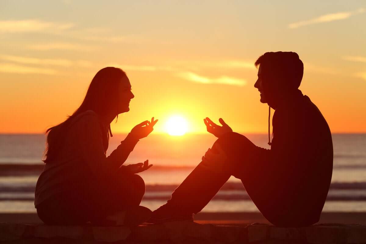 Casal conversando diante do pôr do sol
