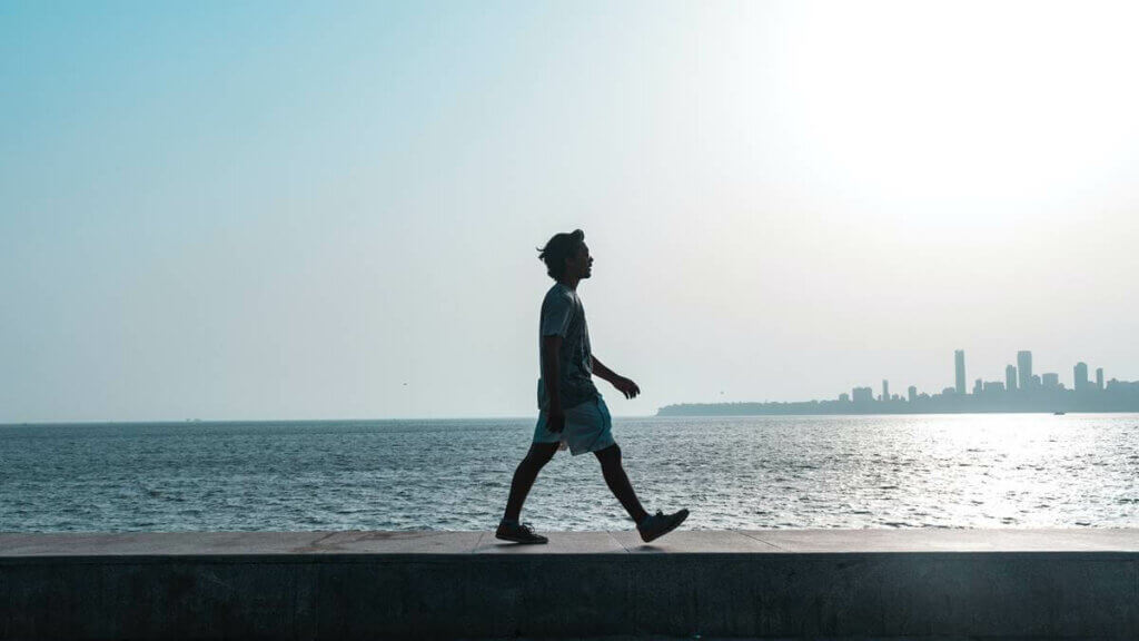 Rapaz caminhando diante do mar