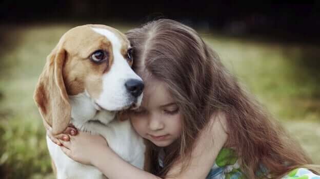 Menina abraçando cachorro
