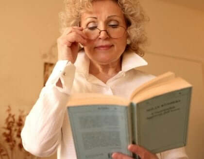 Mulher lendo livro segurando óculos